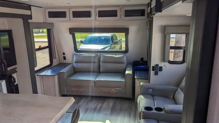 This RV rental's inviting living space boasts a comfy couch, recliners, and large windows with outdoor scenery.. Keystone RV Sprinter Limited 2021