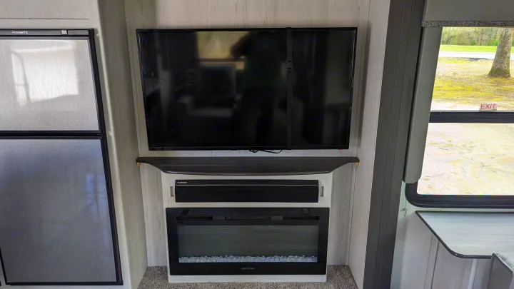 RV rental interior features a Dometic fridge, wall-mounted TV, Furrion soundbar, and Greystone electric fireplace setup.. Keystone RV Sprinter Limited 2021