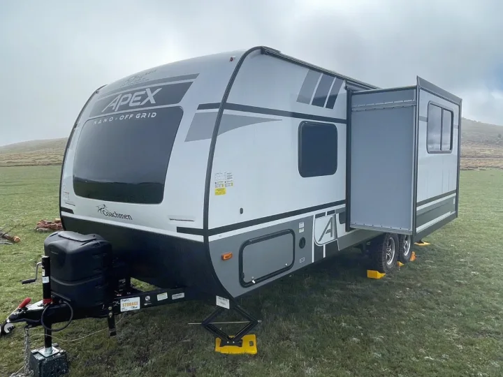 Modern Coachmen Apex Nano RV rental with slide-out extended, set up on green grass. Perfect for off-grid adventures!. Coachmen Apex 2022