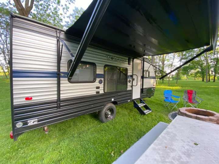 Relaxing at the campground with our rv rental, featuring an extended awning, chairs, and fire pit for cozy evenings.. Forest River Cherokee Wolf Pup 2019