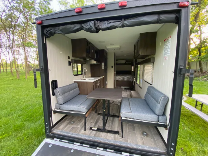Step into this spacious RV rental featuring a dining area, kitchen, and bedroom, viewed from its open rear ramp.. Forest River Cherokee Wolf Pup 2019
