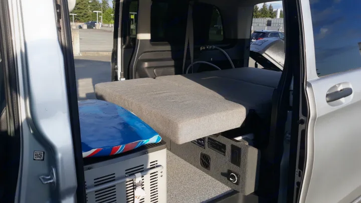 Explore this RV rental's compact camper van interior, featuring a cozy bed, portable fridge, and power station.. Mercedes Metris 2016