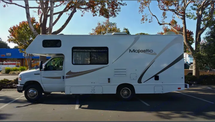 A white Majestic Class C RV rental is parked in a lot on a sunny day, ready for road trips.. THOR MAJESTIC 23a 2018