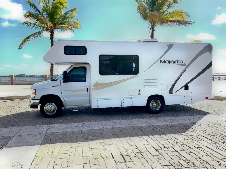 Majestic RV rental parked on pavement near a tropical bay with palm trees under a blue sky.. THOR MAJESTIC 23a 2018
