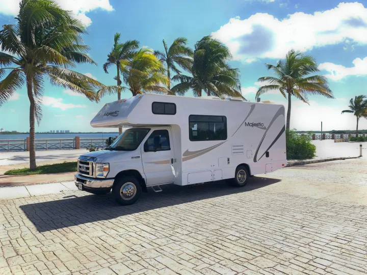 White Majestic RV rental parked among tropical palm trees by the ocean. An ideal motorhome for your sunny vacation.. THOR MAJESTIC 23a 2018