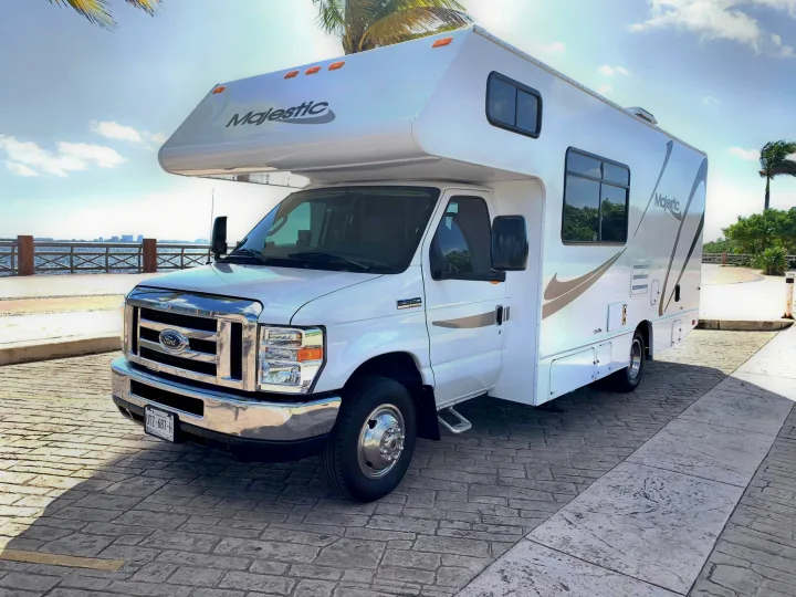 White Majestic RV rental (Ford Class C) parked by the ocean in Mexico. Bright sunny day with palm trees.. THOR MAJESTIC 23a 2018