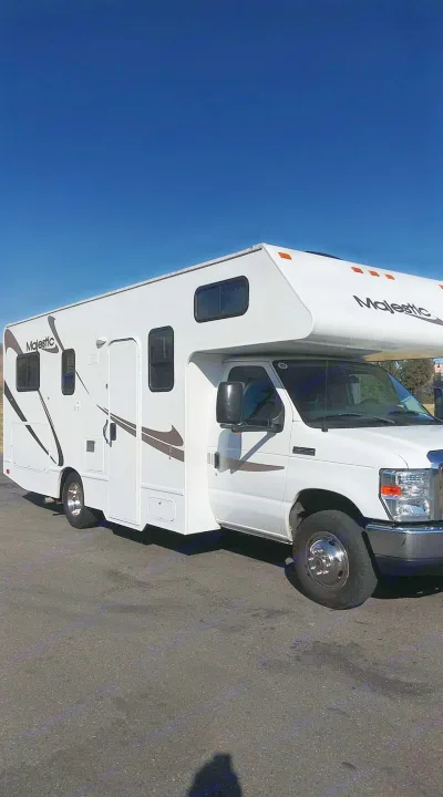 Majestic Class C RV rental, a white motorhome with brown graphics, parked on asphalt under a clear blue sky.. THOR MAJESTIC 23a 2018