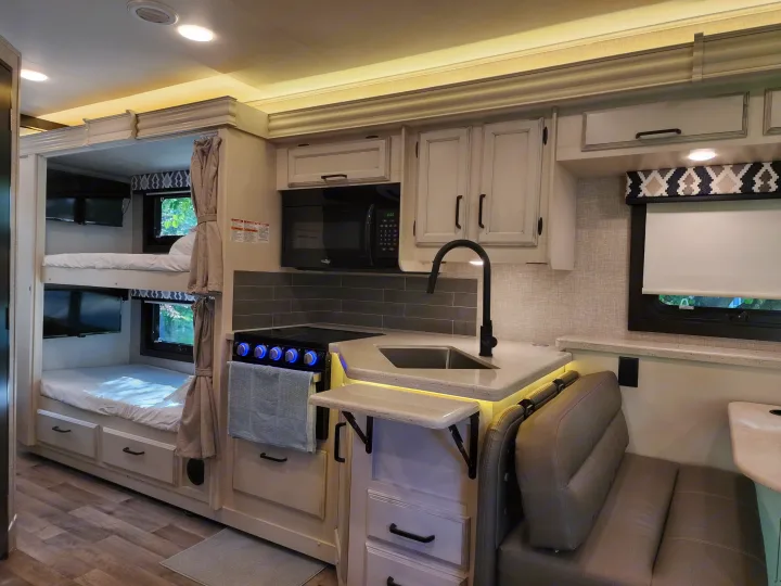 RV rental showing interior with kitchen, bunk beds with TVs, and dining area. Functional and modern design.. Jayco Alante 2022