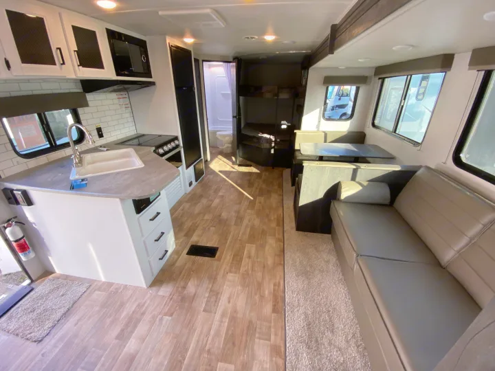 Spacious RV rental interior with a kitchen, dining area, sofa, bathroom, and bunk beds. Bright and modern design.. Keystone RV Hideout 2022