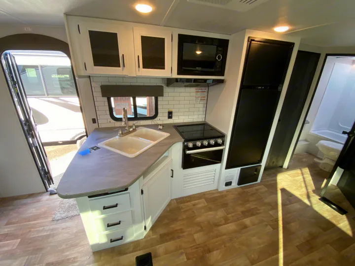 RV rental: Bright, modern kitchen with white cabinets, double sink, microwave, range, & large fridge.. Keystone RV Hideout 2022