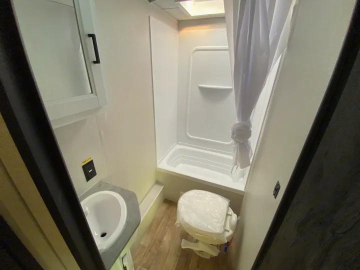 Spotless RV rental bathroom: shower, sink, mirrored cabinet, and a covered toilet. Travel ready!. Keystone RV Hideout 2022