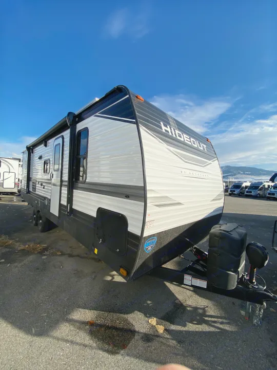 A new Hideout travel trailer, ideal for your next RV rental. Parked under a clear sky on a dealership lot.. Keystone RV Hideout 2022