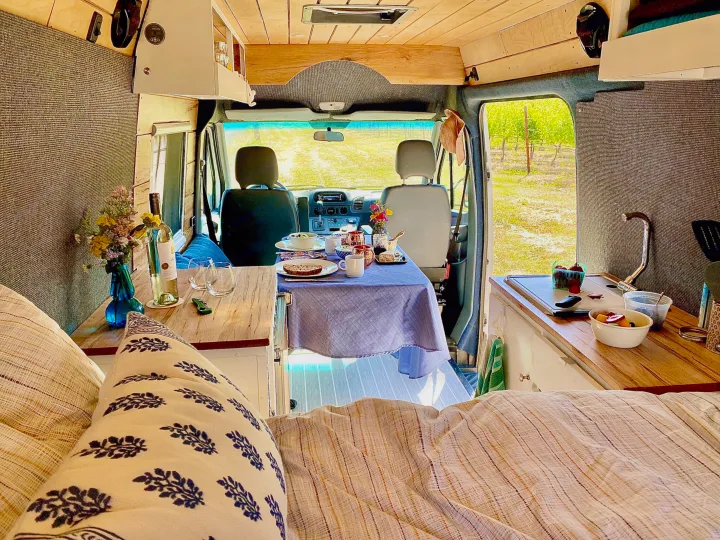 Cozy rv rental interior: dining table set, kitchen, bed, and view to vineyard. Perfect for travel adventures!. Mercedes Sprinter 2005