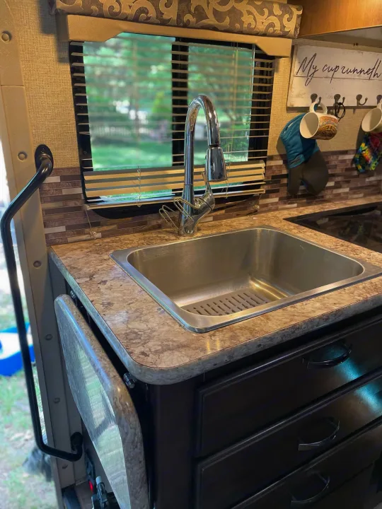 RV rental kitchen with stainless steel sink, patterned countertop, and mosaic tile backsplash.. Thor Four Winds 2018