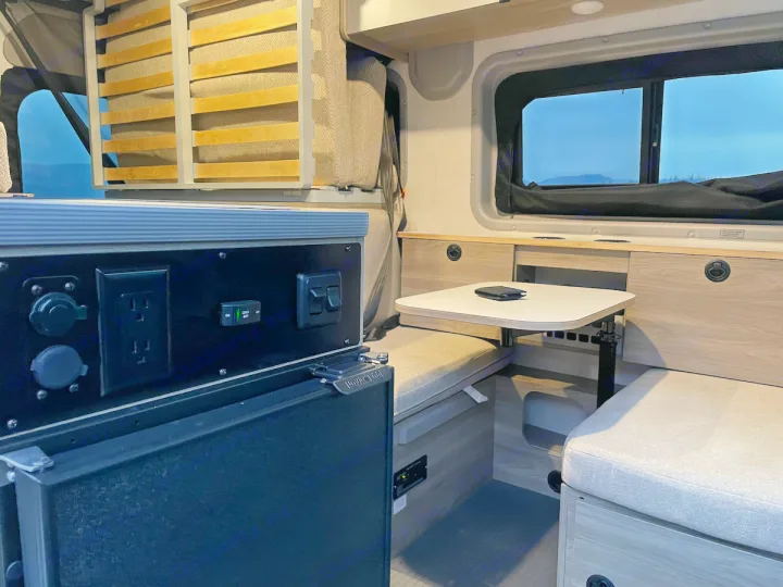 Inside this RV rental: functional dinette seating, power outlets, and a versatile bed for comfortable mobile living.. Winnebago pocket 2023