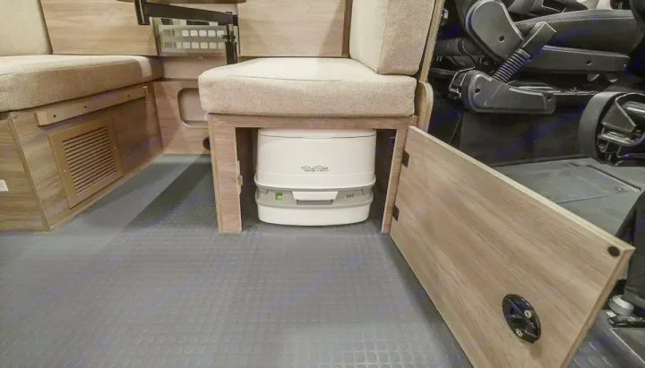RV rental interior reveals a Porta Potti portable toilet hidden under a bench seat, providing essential amenities for compact living.. Winnebago pocket 2023