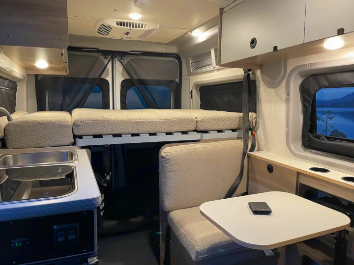 Cozy RV rental interior with convertible bed, kitchenette, and dining area. Perfect for travel adventures!. Winnebago pocket 2023