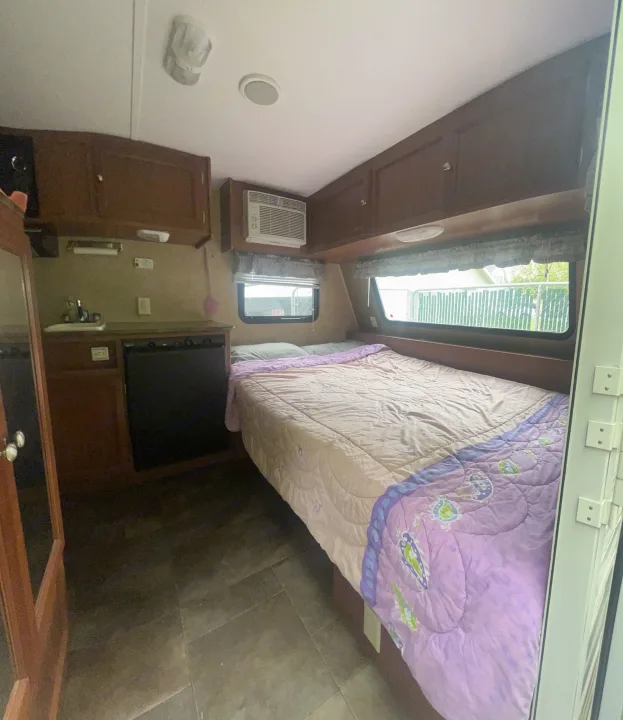 RV rental interior: cozy bed, compact kitchen with sink/stove, and overhead cabinets offer a comfortable and functional space.. Dutchmen Coleman Expedition LT 2013