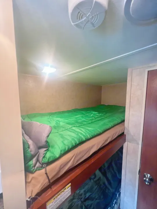 RV rental interior: Cozy bunk beds with green sleeping bags, perfect for family adventures.. Dutchmen Coleman Expedition LT 2013