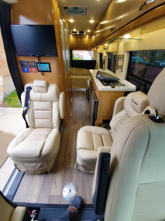 Explore this RV rental's spacious interior: cream leather seats, sleek kitchen, TV, and wood flooring. Ideal for comfortable travel.. Mercedes sprinter 2021