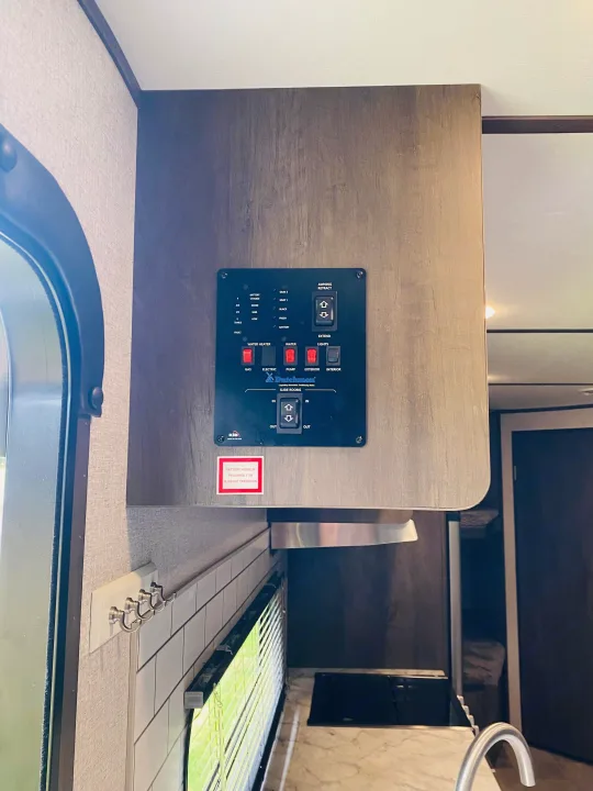 The RV rental's command center on a wood cabinet. It features controls for tank levels, water, lights, and slide rooms.. Coleman Lantern 2021