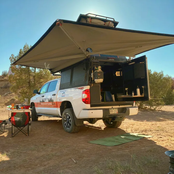 Overland adventure awaits! White truck camper with awning & full setup, an ideal RV rental for off-grid camping.. Toyota Tundra 2021