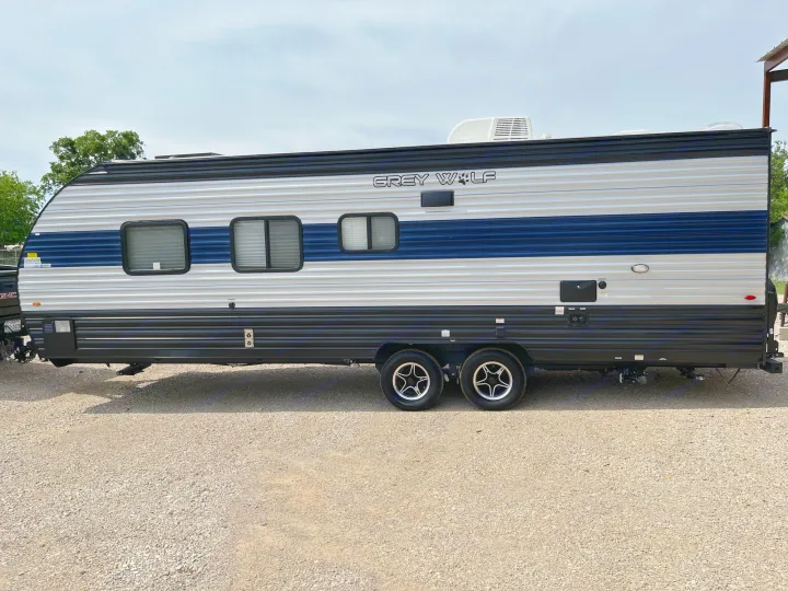 RV rental: A side view of a Grey Wolf travel trailer, gray and blue, on a gravel lot under a cloudy sky.. Forest River Cherokee Grey Wolf Special Edition 2022