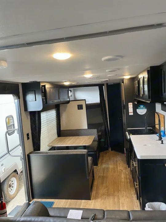 Modern rv rental interior with a fully equipped kitchen, dinette, and living area. Features dark cabinets and light wood floors.. Forest River Cherokee Grey Wolf Special Edition 2022