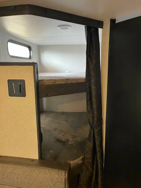 RV rental interior: two bunk beds with a window, privacy curtain, and power outlet, perfect for sleeping.. Forest River Cherokee Grey Wolf Special Edition 2022