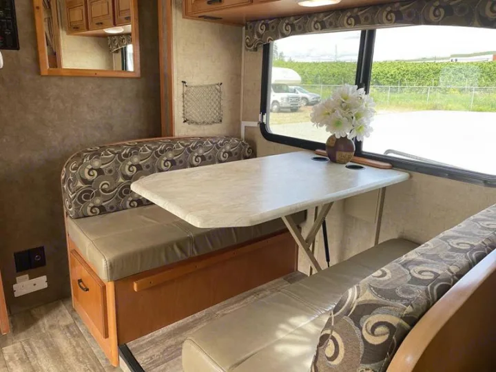 Spacious RV rental interior featuring a cozy dinette with patterned cushions, a table, and a window view.. Sunseeker 2650 2015