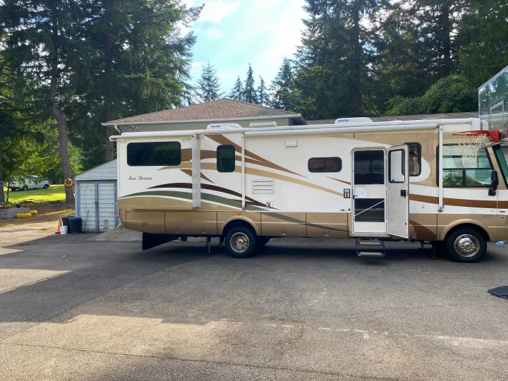 Spacious Sea Breeze RV rental parked on a driveway with its side expanded and door open, ready for use.. National RV Sea Breeze 2006