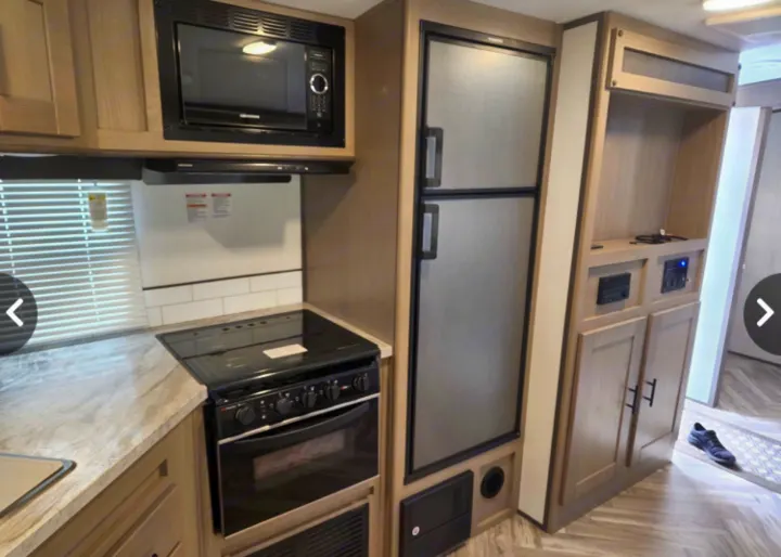RV rental kitchen: modern interior with built-in microwave, stove, refrigerator, and entertainment/control hub.. Cruiser Rv Corp Shadow Cruiser 2021