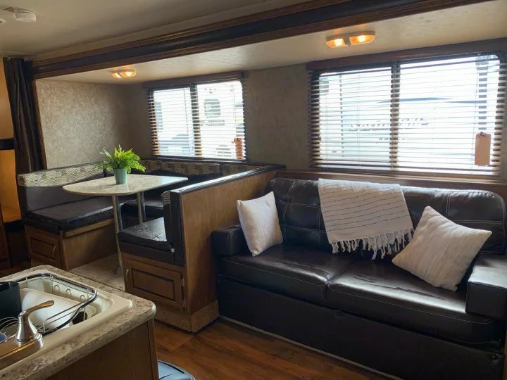 Explore this comfortable RV rental interior, featuring a cozy dining booth, sofa, and practical kitchen setup for travel.. Forest River Wildwood X-Lite 2016