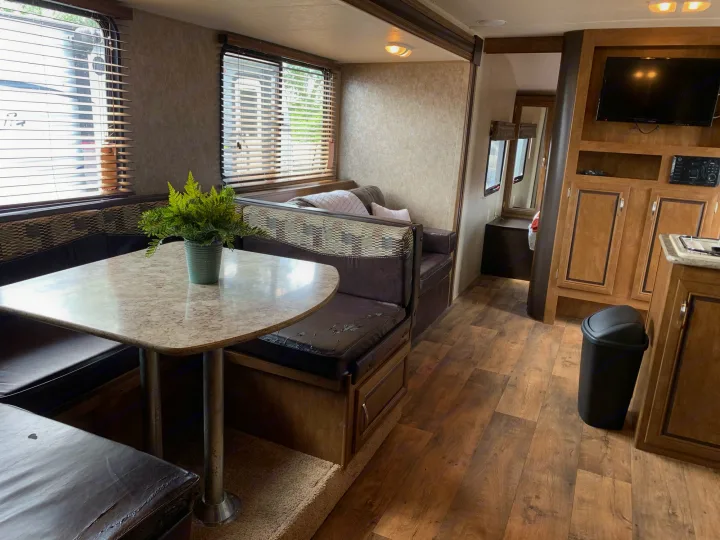 This inviting RV rental interior features a cozy dinette, comfortable sofa, and kitchen space, ready for your adventures.. Forest River Wildwood X-Lite 2016