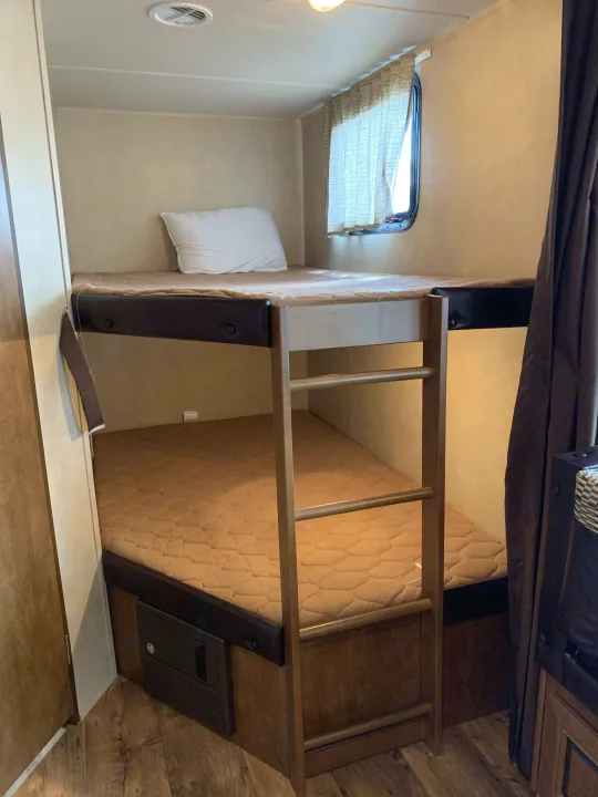 RV rental: Bunk beds with ladder, window, and mattresses, offering a compact sleeping area.. Forest River Wildwood X-Lite 2016