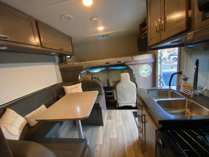 Spacious rv rental interior: modern dinette, full kitchen, and cab-over bunk bed for comfortable travels.. Winnebago Minnie Winnie 2020