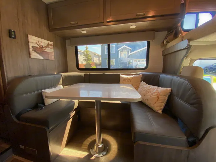 Spacious RV rental dinette with comfortable U-shaped seating, table, and large window views, ideal for meals & relaxation.. Winnebago Minnie Winnie 2020