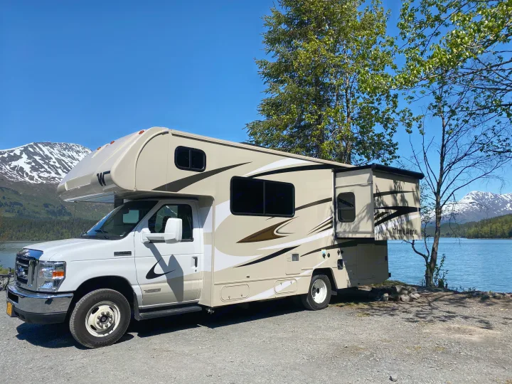 Winnebago RV rental parked by a clear lake & snowy mountains, ready for your next scenic camping trip.. Winnebago Minnie Winnie 2020