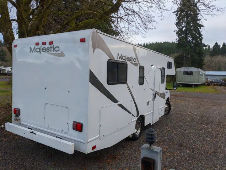 White Majestic motorhome, ideal for an rv rental, parked on gravel with trees in the background.. Thor Four Winds 2013
