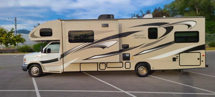 Beige Jayco Greyhawk RV rental, slide-out extended, parked. Ready for your next adventure.. Jayco Greyhawk 2015