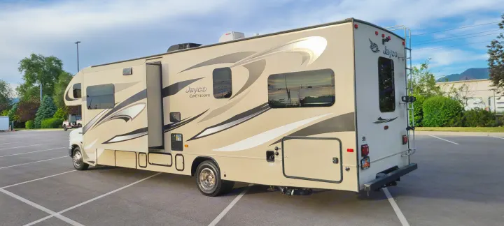 Spacious tan Jayco Greyhawk RV rental parked in a lot, highlighting its rear and side. Ready for adventure.. Jayco Greyhawk 2015