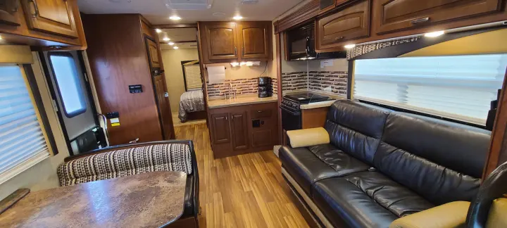 This spacious RV rental interior features a full kitchen, comfortable living area with couch & dinette, and a cozy bedroom.. Jayco Greyhawk 2015