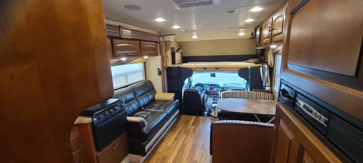Inside an RV rental: features a comfy sofa, kitchen, dining area, and overhead bunk.. Jayco Greyhawk 2015
