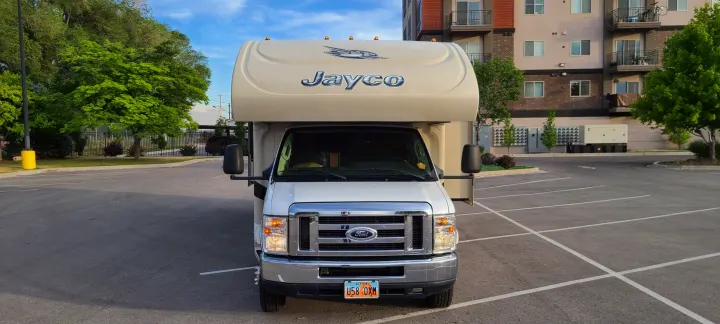 White Jayco Class C RV rental parked in a lot, ready for Utah adventures.. Jayco Greyhawk 2015