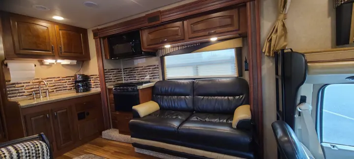 This RV rental features a full kitchen with microwave, sink, stove, and a comfy living area with sofa.. Jayco Greyhawk 2015