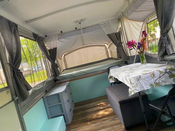 Cozy pop-up camper interior, ideal for your next rv rental. Features a bed, dining area, and charming decor.. Coleman Grand Tour Sun Valley 2002