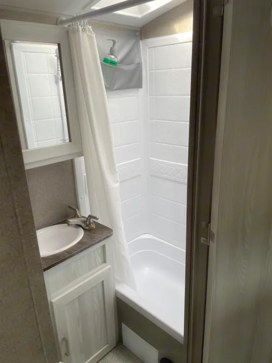 A clean, functional RV rental bathroom featuring a shower/tub combo, vanity with sink, and mirror.. Forest River Flagstaff E-Pro 2020