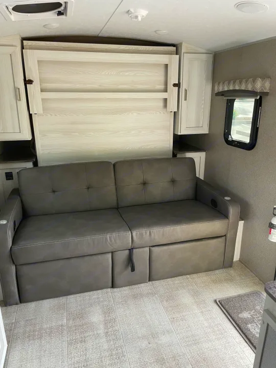 RV rental: Gray sofa, folded murphy bed, window, and fire extinguisher create a functional interior.. Forest River Flagstaff E-Pro 2020