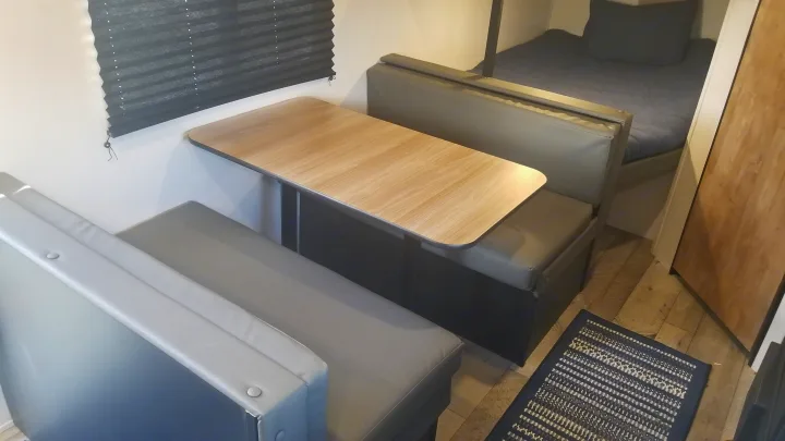 Cozy RV rental interior featuring a practical dinette with a table and a comfortable bunk bed setup. Ready for travel!. Keystone RV Springdale 2022