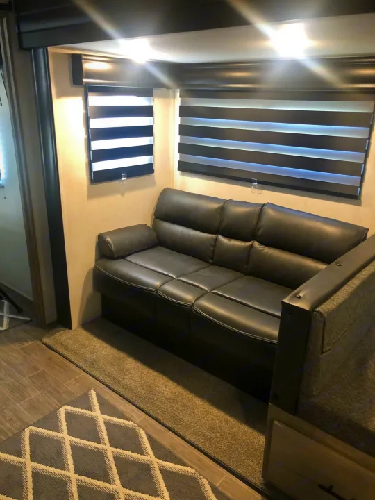 Inside an RV rental: a plush dark leather sofa, zebra blinds, and tiled floor make for a cozy travel space.. Forest River Cherokee Alpha Wolf 2022